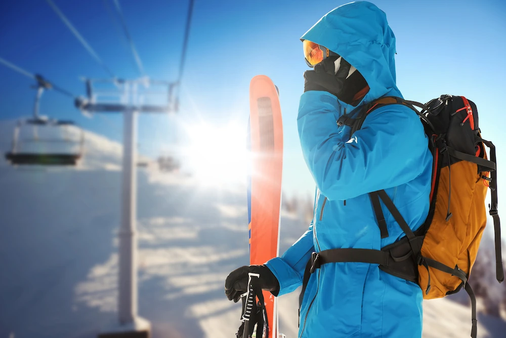Skid�kare som pratar i telefon i backen med lift i bakgrunden